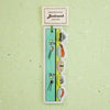 A hanging bookmark shaped like a sushi train, with cartoon sushi illustrations and a small paper header card that reads 'Bookmark' and 'Sushi Train,' shown against a pale green textured background.