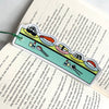 A sushi-themed bookmark with a cartoon sushi illustration and a green string, shown resting on an open book.