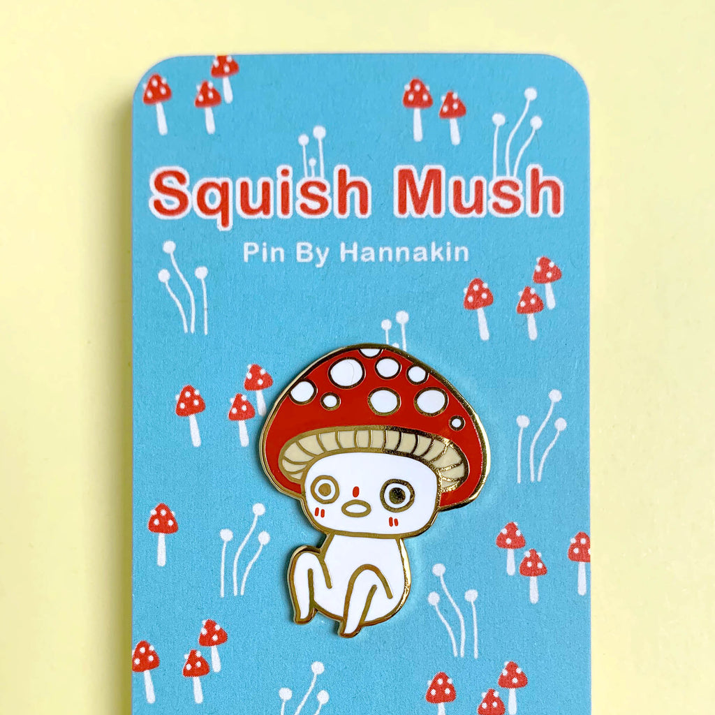 Enamel pin of a cartoon mushroom character on a blue card with 'Hannakin' branding.