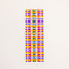 A rectangular postcard featuring a colourful plaid print on a off-white background. 