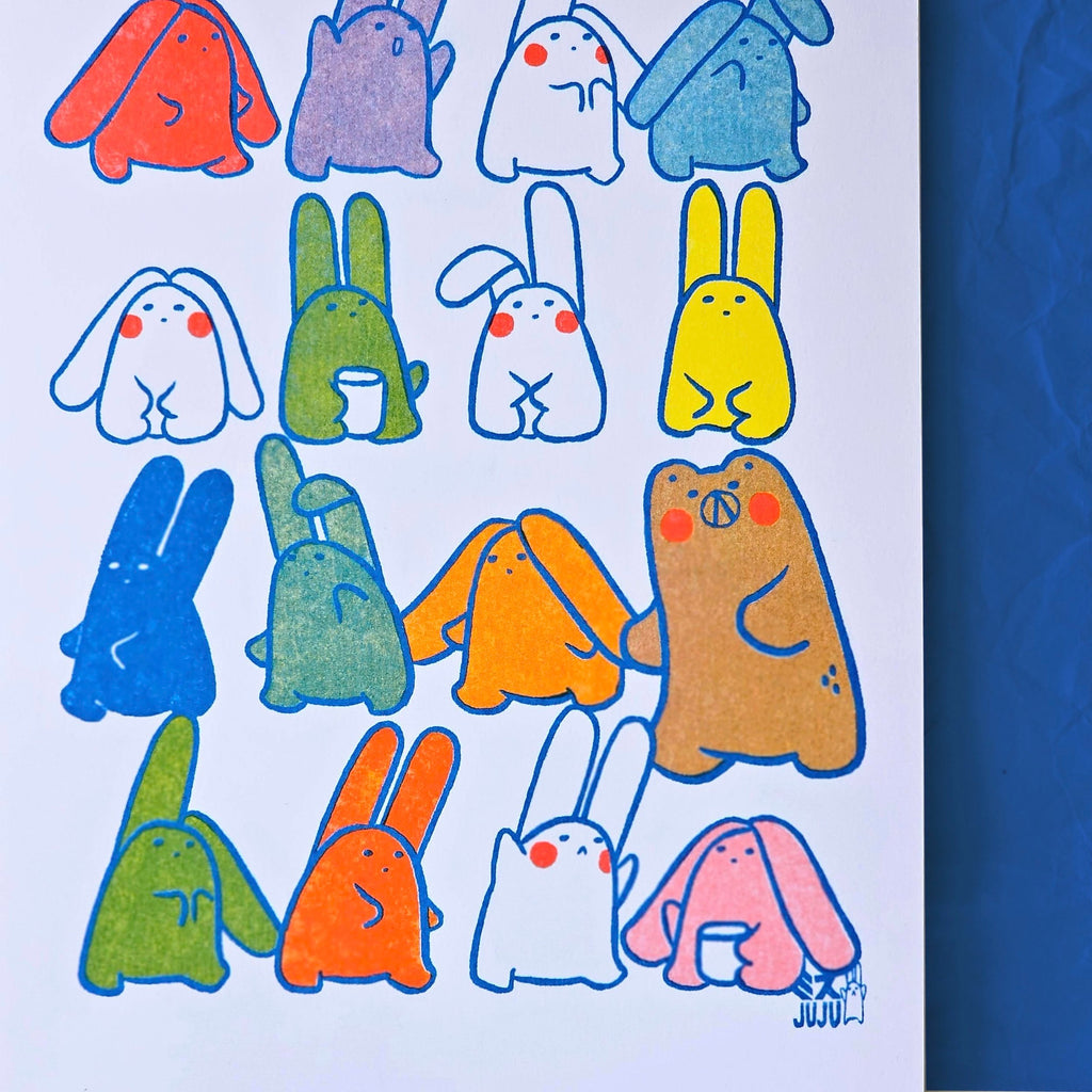 A white art print featuring a grid of colourful cartoon rabbits and creatures with blue outlines, displayed against a textured blue background.