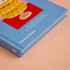 A blue book featuring a picture of a cake on a peach background