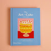A book titled 'The Art of Cake" on a peach background