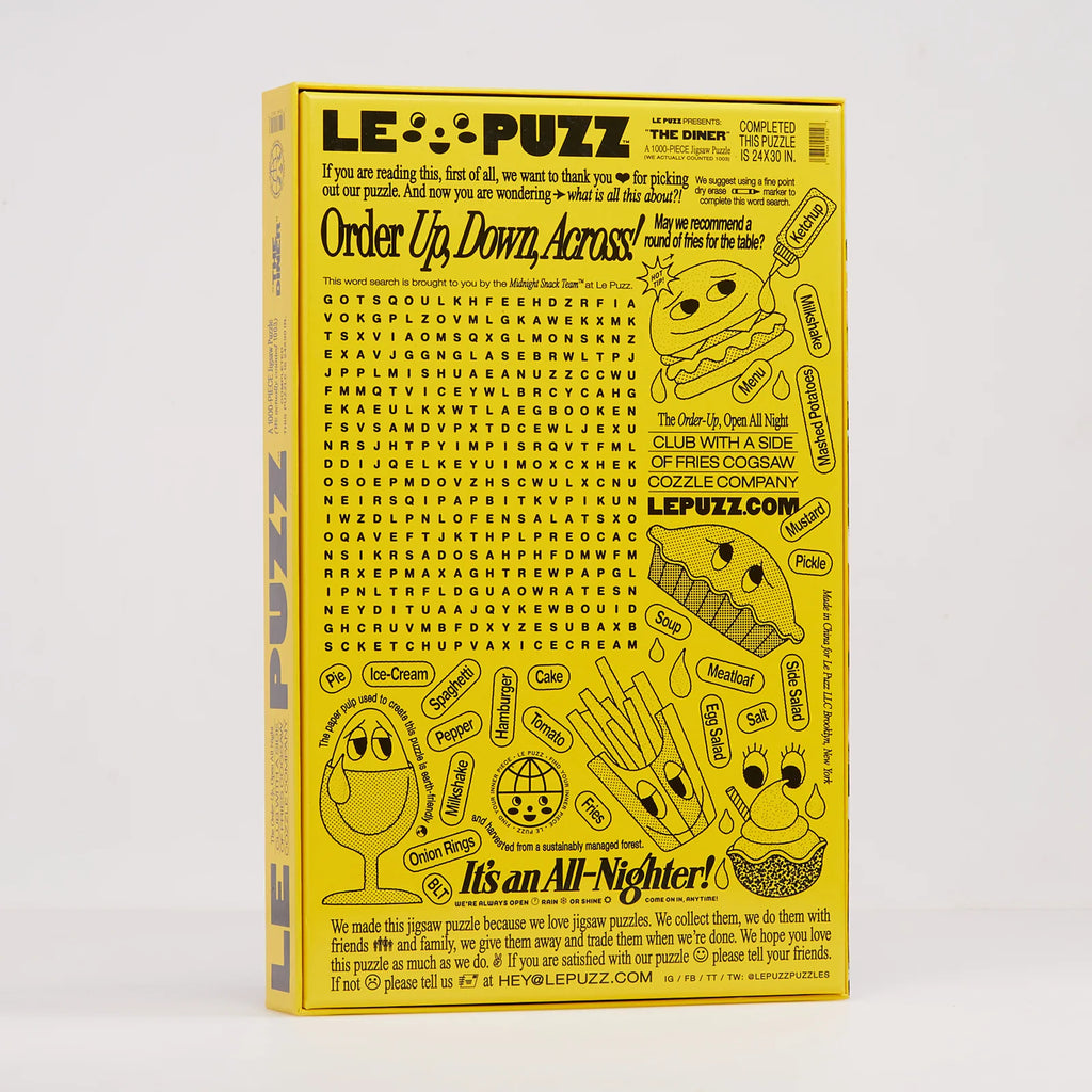 A yellow crossword titled 'It's an All-Nighter' shown standing upright against a light grey background. The cover features multiple food illustrations and black text, with the LE PUZZ brand name prominently displayed at the top and bottom.