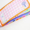 A close-up of a colourful notepad, showing a pink and white gingham notepad with a cute white dog illustration and an orange border, alongside other colourful paper sheets.