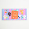 A rectangular notepad featuring a colourful illustration of several dogs reading books on pink and blue vertical stripes, with a central orange book reading 'THE GOOD DOGS' and 'by TADA REIKO'.