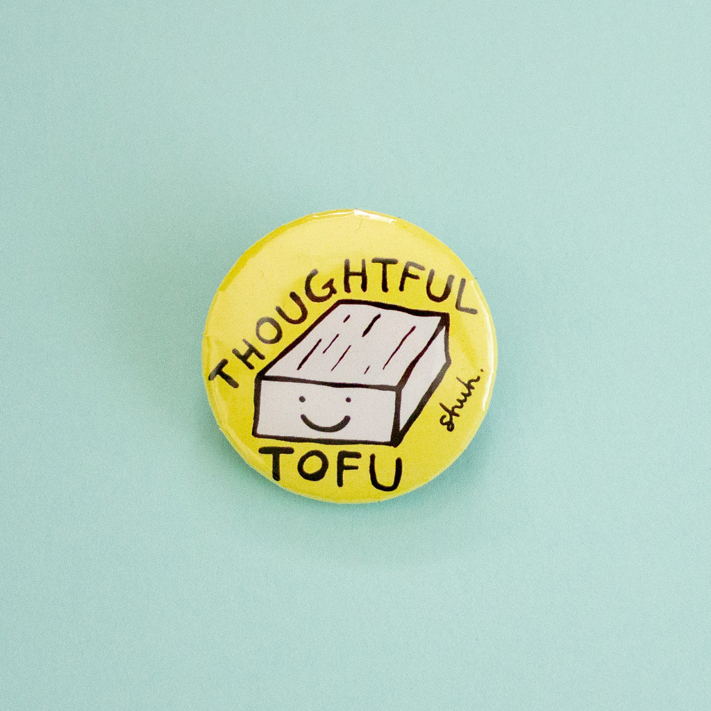 A round yellow pinback button featuring a hand-drawn illustration of a smiling tofu block with the words 'THOUGHTFUL TOFU' in black lettering, set against a solid light blue background.
