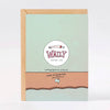 A greeting card with a kraft paper envelope, featuring a textured mint green front with a circular logo for 'Wally Paper Co'.
