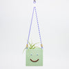 Green hanging planter with a smiley face design on a white background