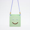 Green square-shaped hanging ornament with a smiley face on a white background