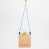 Smiley face planter with a hanging string on a light gray background