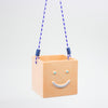 Square ceramic hanging planter with a smiley face and blue swing ropes on a light gray background