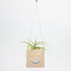 Square hanging planter with a smiley face design on a white background