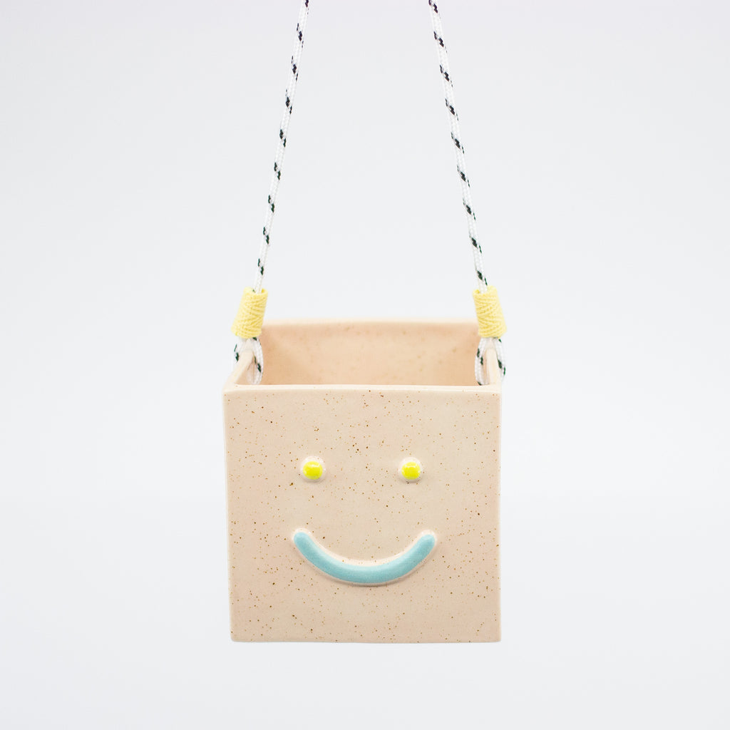 Peach rectangular hanging basket with a smiley face design on a white background