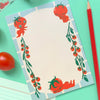 A flat-lay of a notepad with a cute tomato-themed border design, styled on a mint green background with a red pencil, cherry tomatoes, and a roll of patterned tape.
