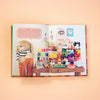Open book with illustrations of a teddy bear, small figures, and colourful items on a table against a peach background.