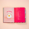 Open book with a pink page featuring an egg plush toy and text on a peach background