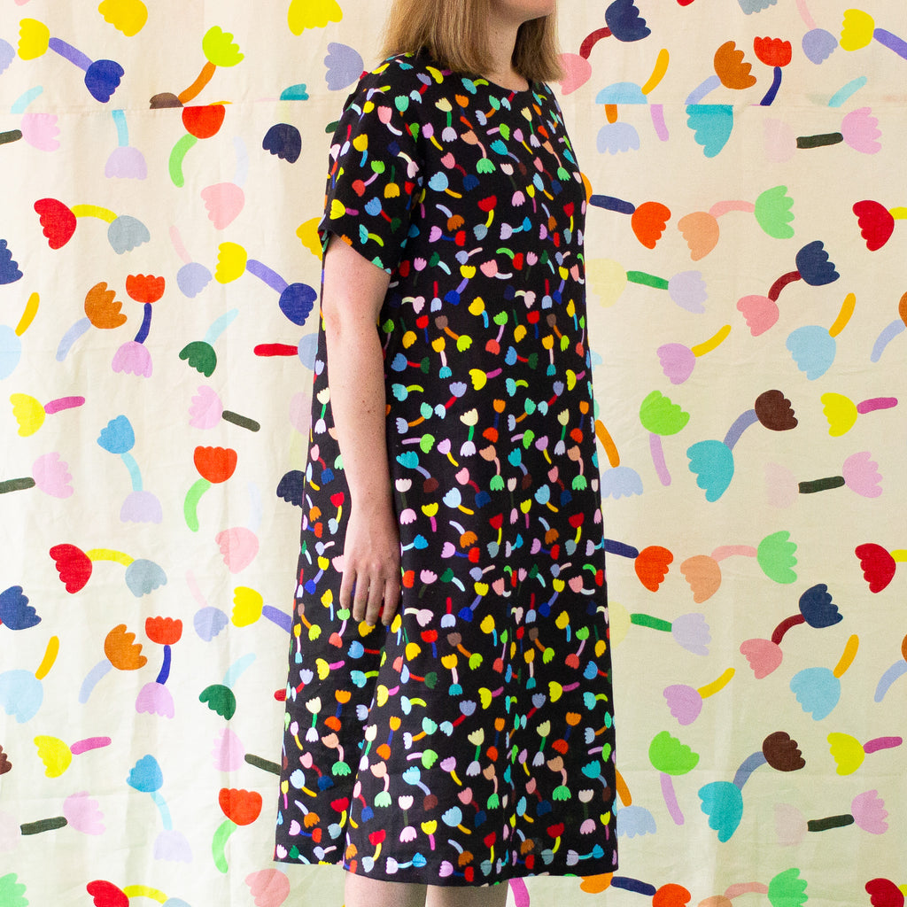 A front view of the Tulip linen dress. Multicoloured tulips on a black background.