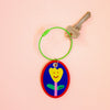 Keychain with a colourful design of a flower on a peach background
