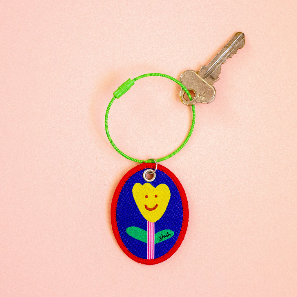Keychain with a colourful design of a flower on a peach background