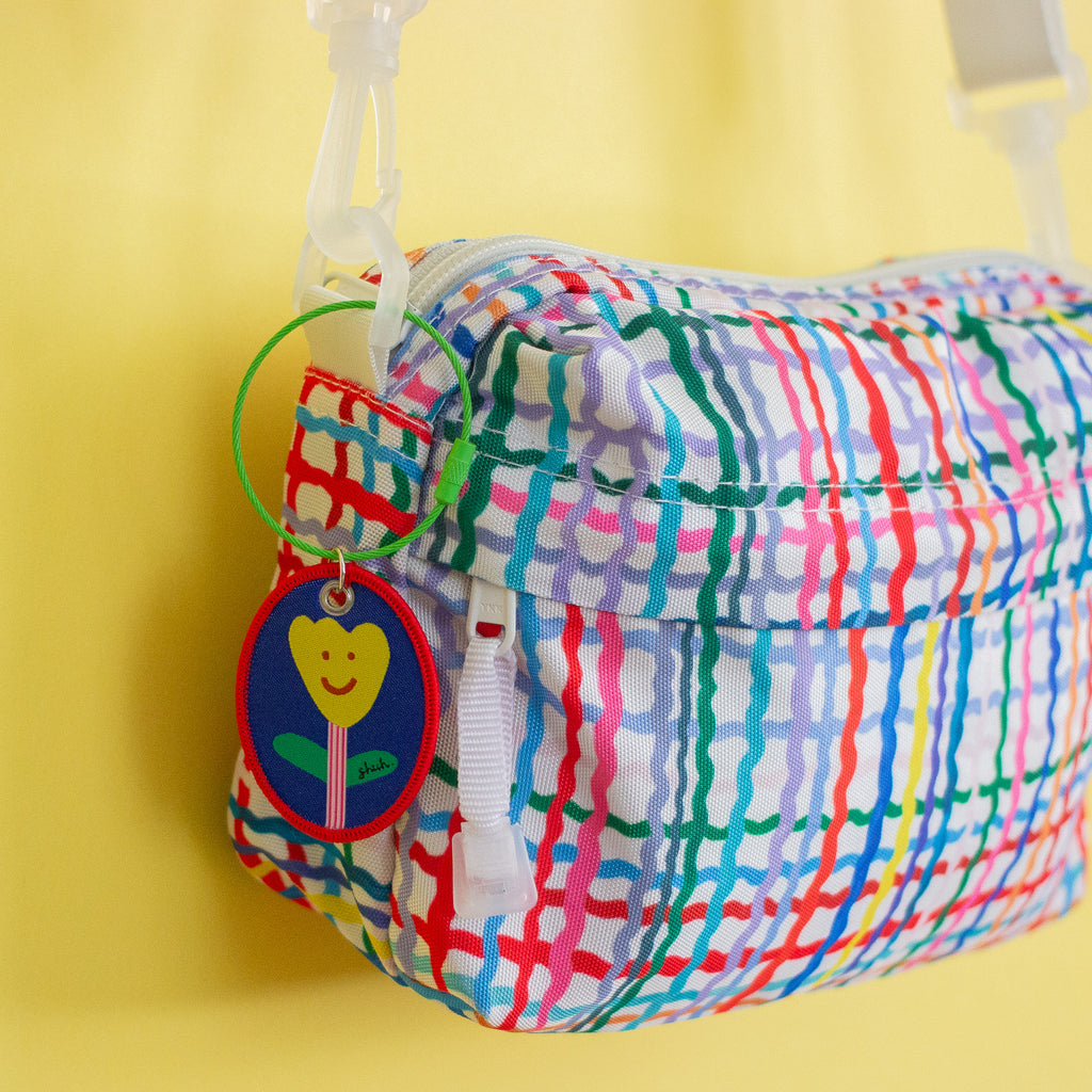 Colourful plaid pouch with a keychain on a yellow background