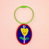 Keychain with a colourful design of a smiley face on a peach background