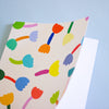 Front view of the tulip notebook. Cover has multicoloured tulip motif on cream background. Also shows inside with blank white pages. 
