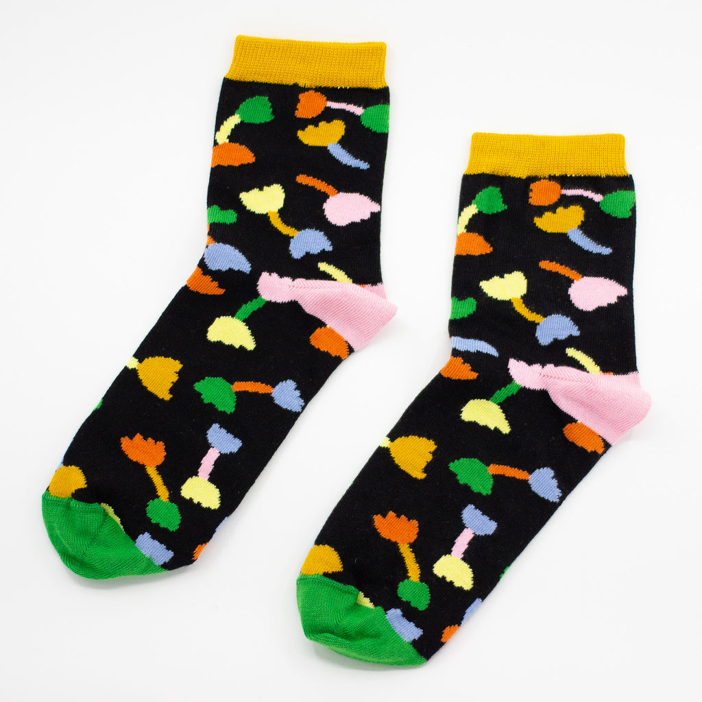 Seperated view of the shuh. Tulip socks. Pink heel, green toe, black background and muliticoloured tulip motifs. 