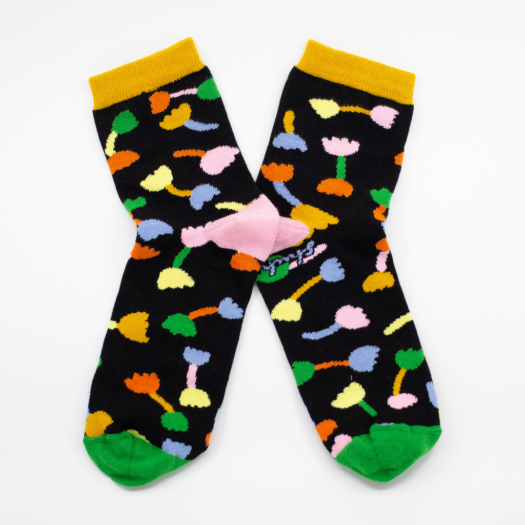 Side view of the shuh. Tulip socks. Pink heel, green toe, black background and muliticoloured tulip motifs. 