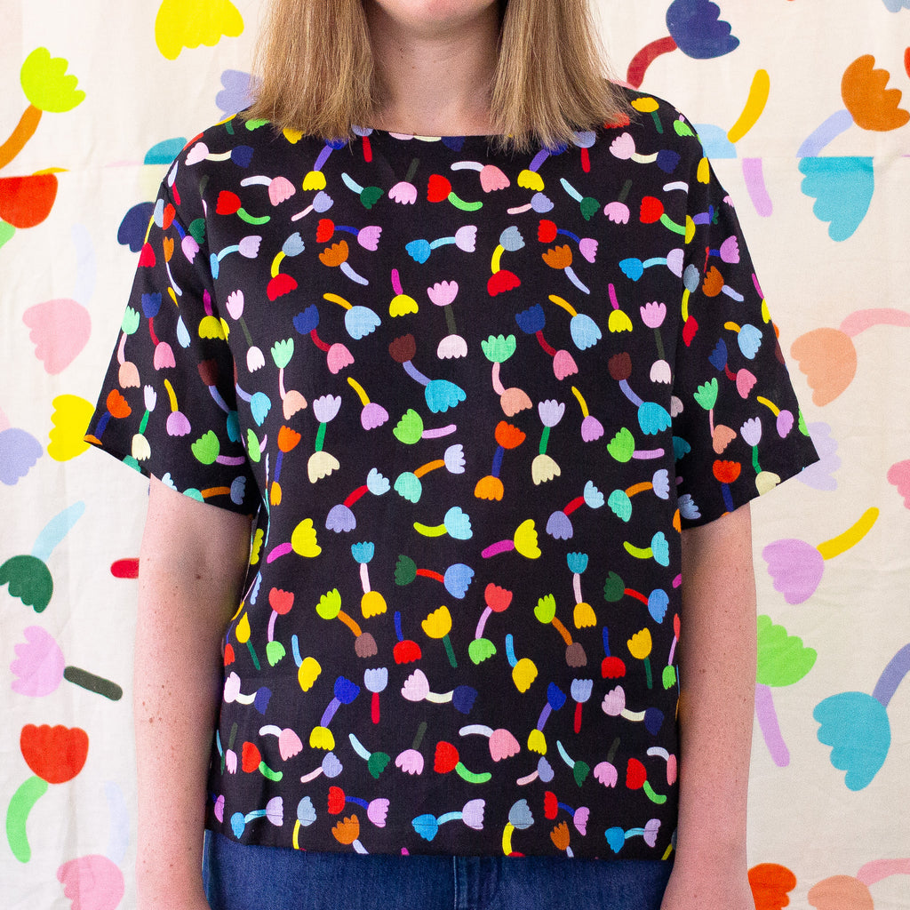 Another Front view of the Tulip Linen top, with black background. Multicoloured repeated tulip motifs. 