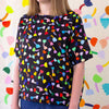 A Front view of the Tulip Linen top, with black background. Multicoloured repeated tulip motifs. 