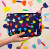 A Hand holding up the tulip useful bag. Repeating colourful tulips on a black background. 