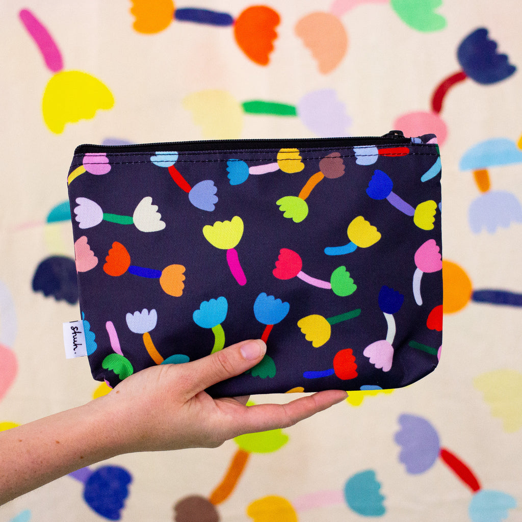 A Hand holding up the tulip useful bag. Repeating colourful tulips on a black background. 