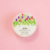 A round container of Tulips Washi Tape by Draw Me In Style, featuring a colourful tulip illustration on a white background, set against a solid pink backdrop.