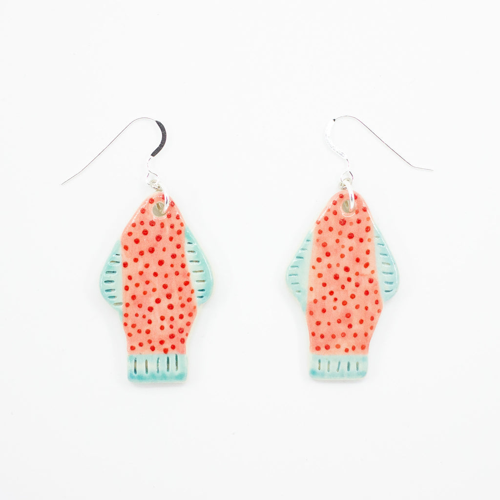 Closeup picture of the Umi earrings, with sterling silver hooks and ceramic beads. Handmade and hand painted ceramic beads are fish shaped, with light blue fins and tail, and pastel pink coloured body with polk dots. 
