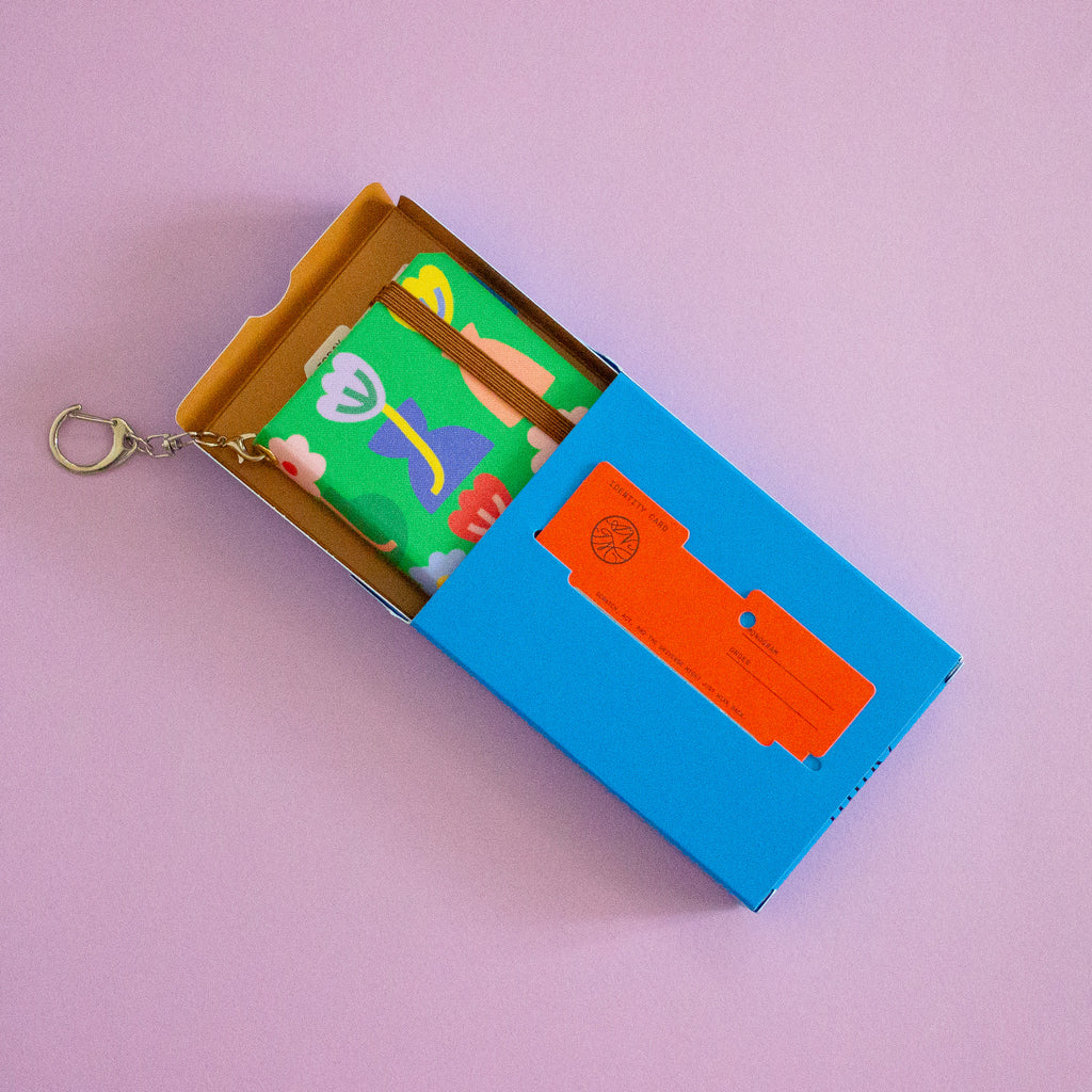 Colorful keychain with a small notebook in a blue box on a lilac background