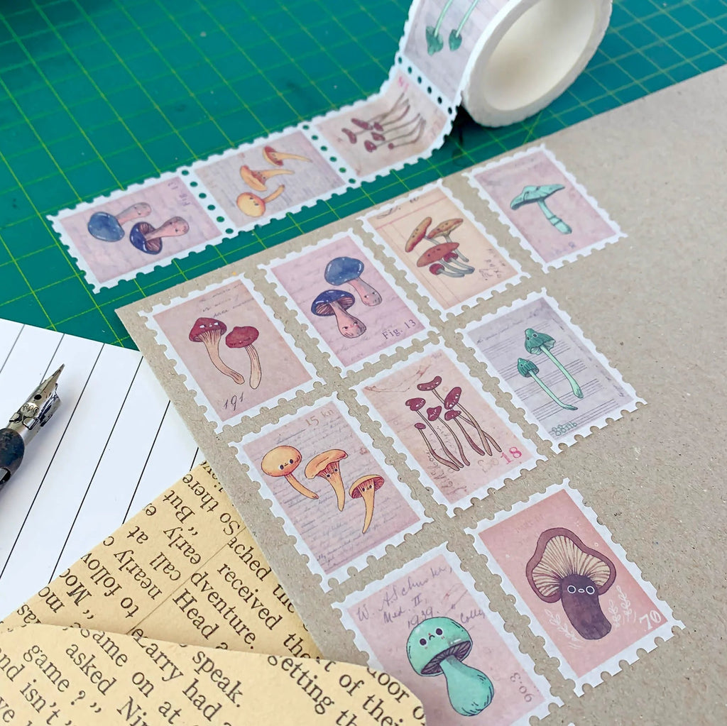 Mushroom-themed stamps on a cutting mat with a roll of tape and pen.