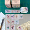 A set of vintage-style mushroom-themed washi tape rolls and individual strips laid out on a green cutting mat, with two paper boxes at the top. The tape and stickers feature illustrated mushrooms in muted pastel colours including pink, purple, blue, and green.