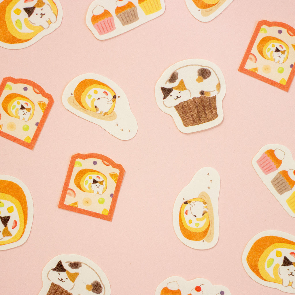 A flat-lay view of cute die-cut stickers featuring cartoon animals in toast, cupcake, and egg shapes, arranged on a solid pastel pink background.