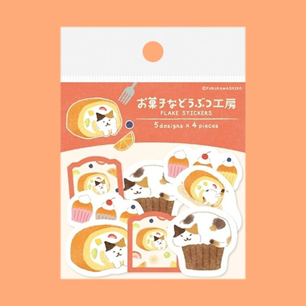 A package of cute cat-themed cake and cupcake stickers on a solid peach-orange background. The packaging is white and coral pink, featuring illustrations of a cat inside a cake roll and cupcakes.