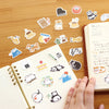Collection of colourful stickers on a wooden surface with a notebook.