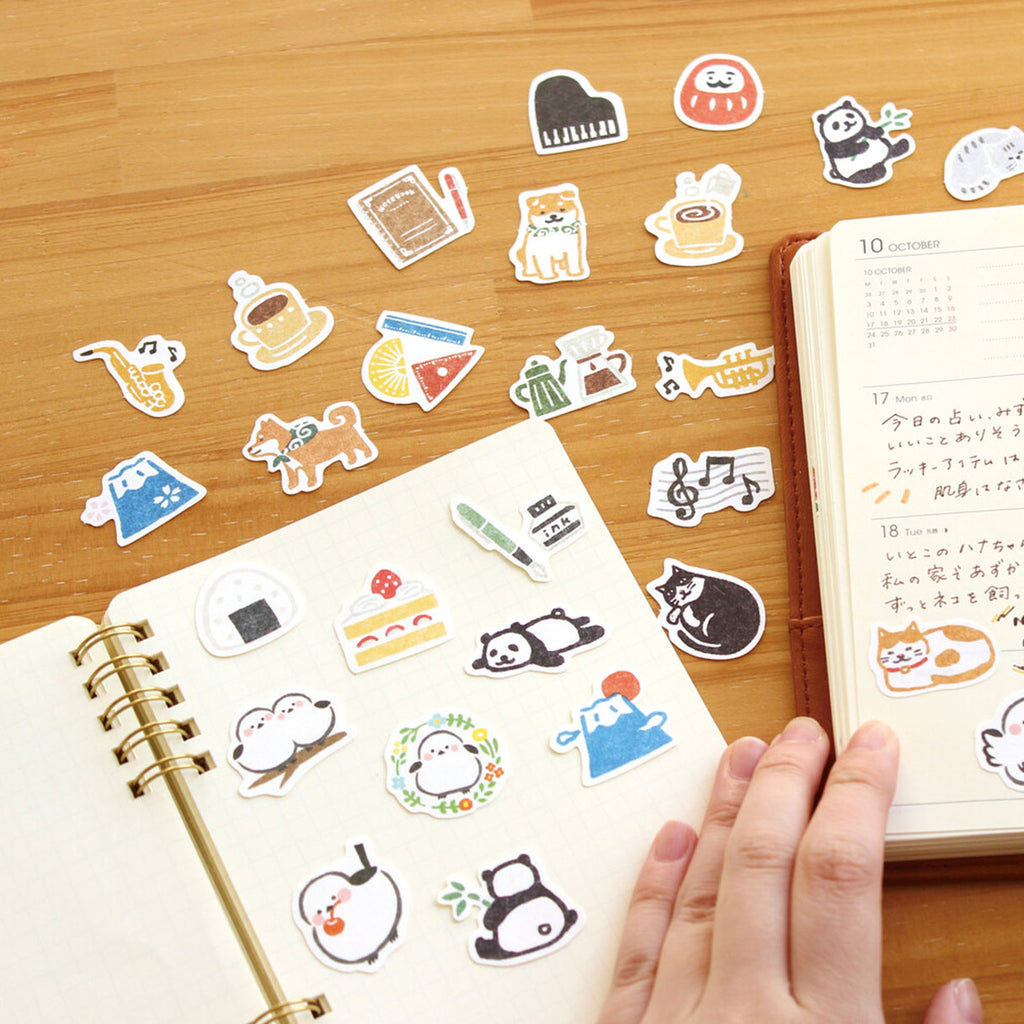 Collection of colourful stickers on a wooden surface with a notebook.