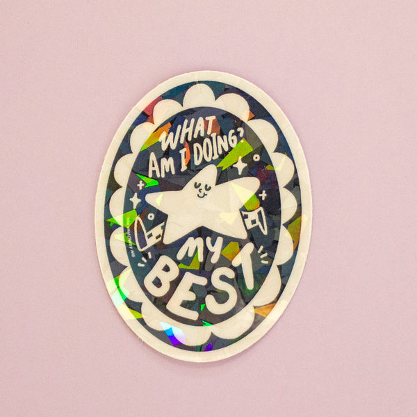 An oval holographic sticker featuring a star illustration with 'What Am I Doing? My Best' text. 
