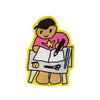 A cartoon-style die-cut sticker or patch showing a figure drawing at a table, with a bright yellow border, pink shirt, black cap, brown skin tone, black outlines, and white paper on a plain white background.