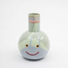 Ceramic vase with a smiley face design on a white background