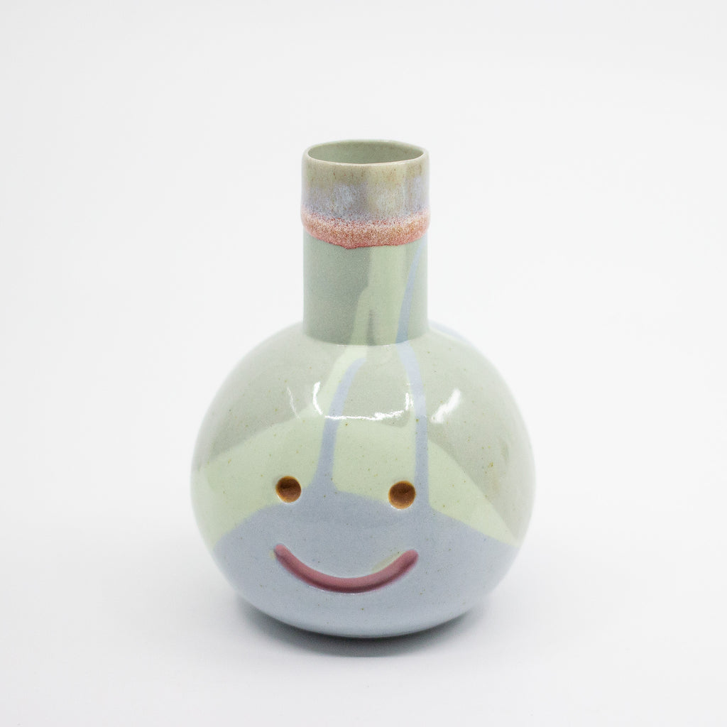 Ceramic vase with a smiley face design on a white background