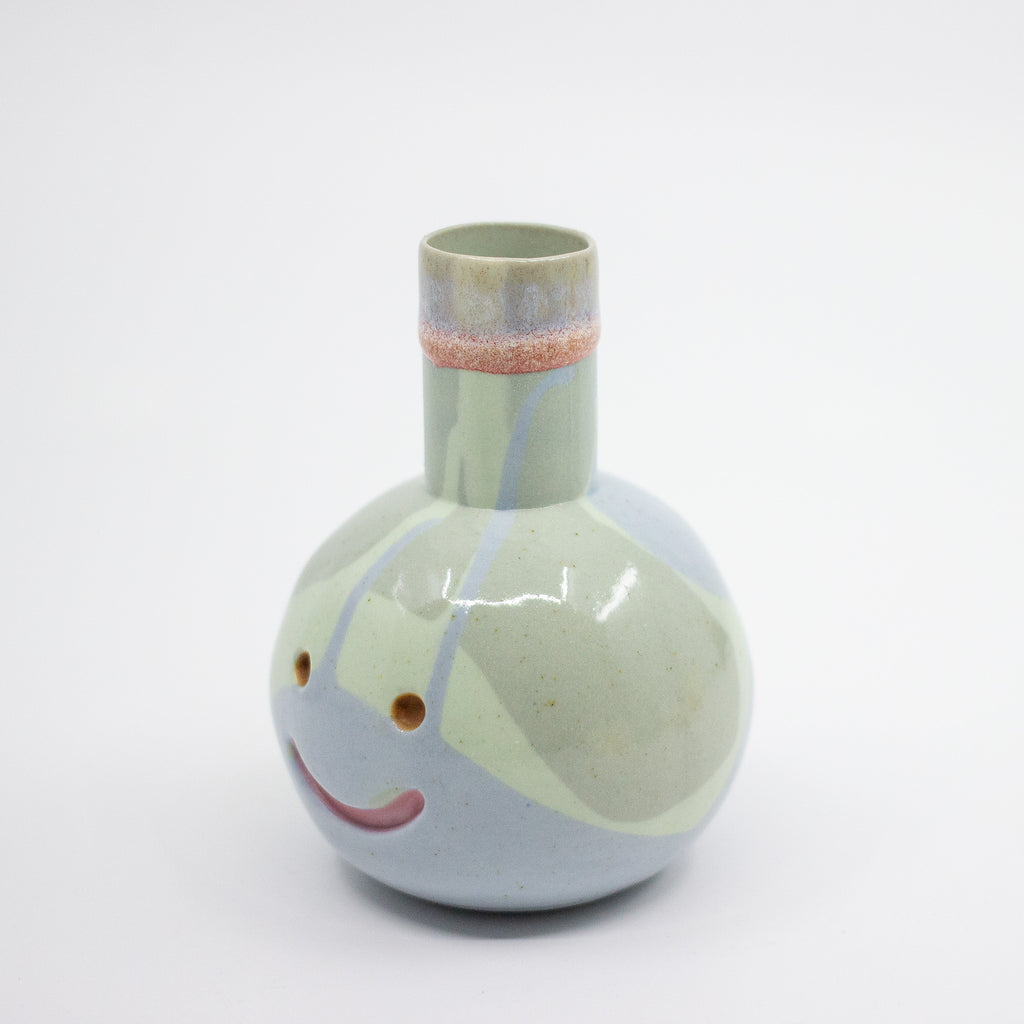 Ceramic vase with a face design on a white background