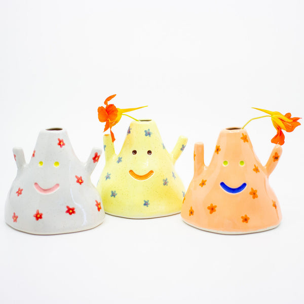Three colorful ceramic vases with smiling faces on a white background