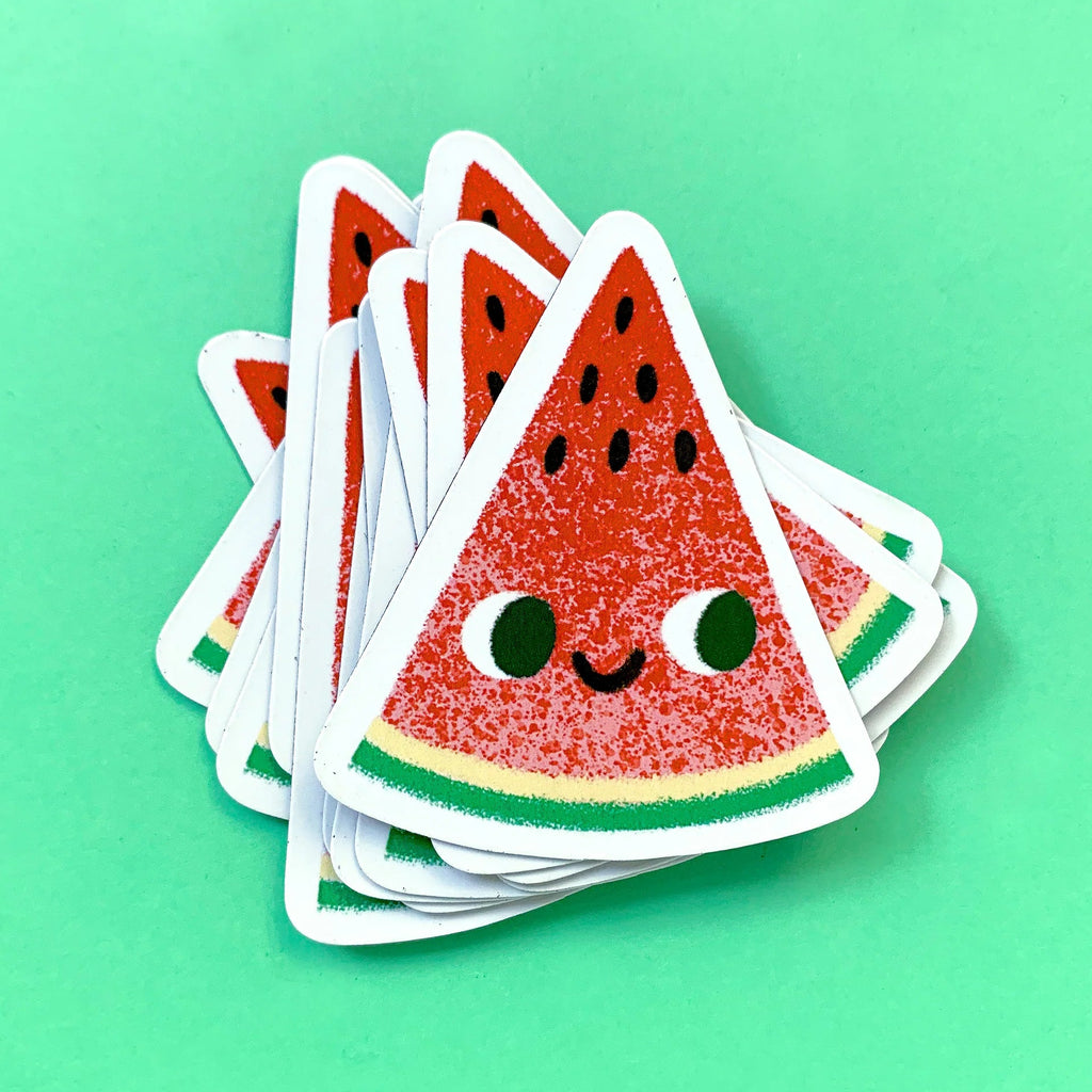 Stack of watermelon slice magnets with a smiling face on a green background