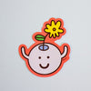 A die-cut sticker featuring a cute cartoon character with a yellow flower on its head, set against a plain light grey background.